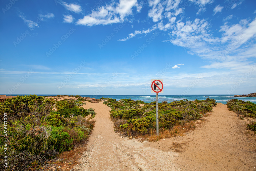 Warning sign of cliff erosion near ocean beach in Australia