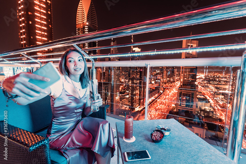 Photography A girl blogger in a rooftop bar takes a selfie photo against the background of a