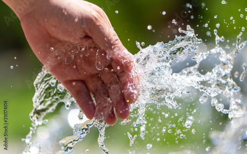 Hand of a man in the spray of water of the fountain