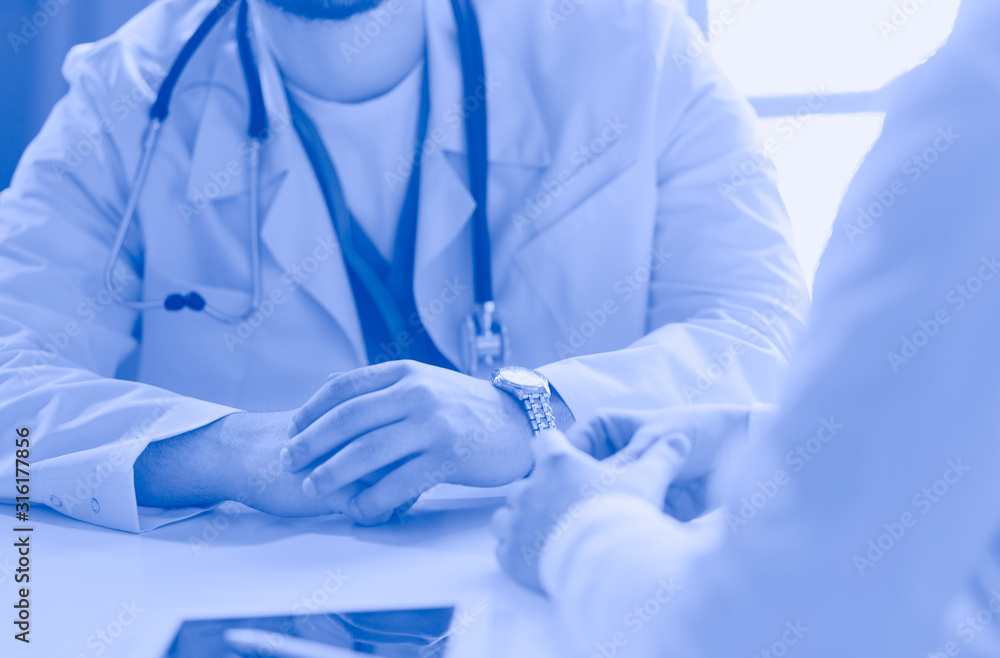 Portrait of a male doctor with laptop sitting at desk in medical office Portrait of a male doctor with laptop sitting at desk in medical office