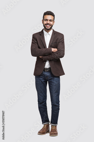 Handsome smiling young man full length studio portrait, isolated on gray background
