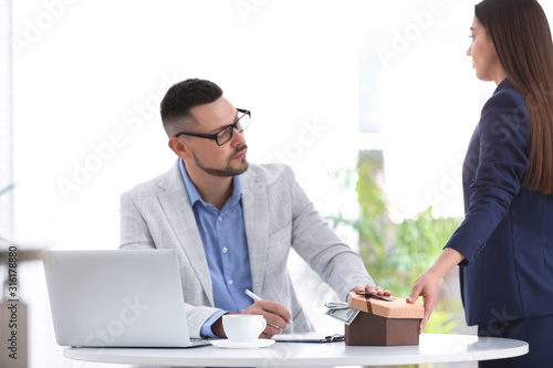 Fotografie Woman giving bribe to man at table indoors