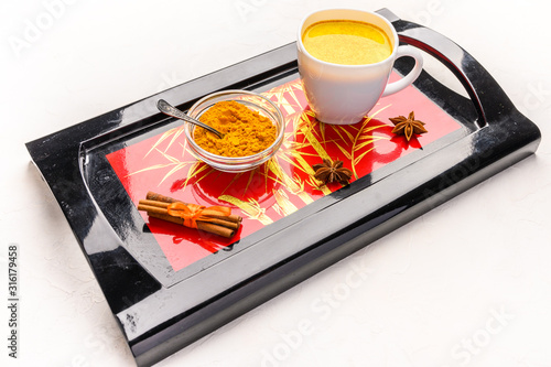 Traditional Indian masala tea chai with spices, cinnamon, anise and cardamom in a white cup on an original black tray