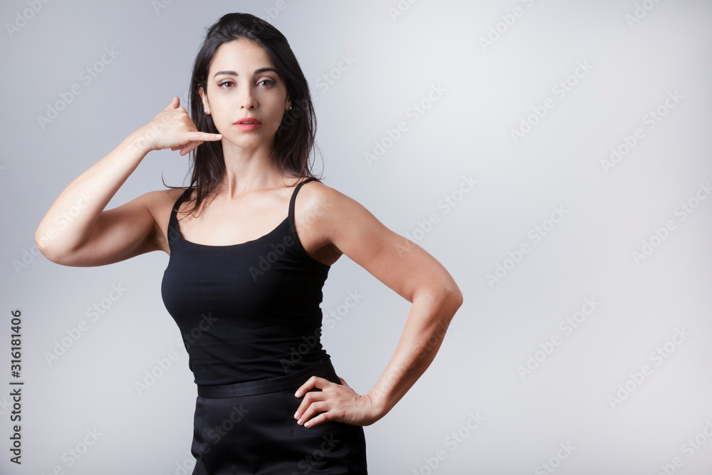 bella e giovane donna fa il segno del telefono con le mani - isolata su sfondo grigio bella e giovane donna fa il segno del telefono con le mani - isolata su sfondo grigio