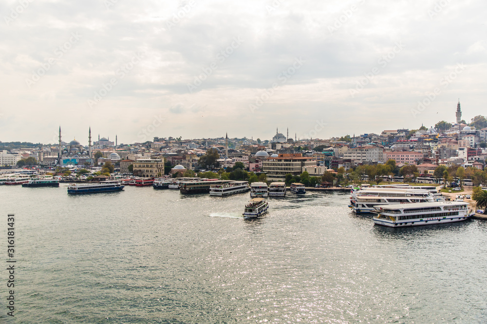 Naklejka premium Tourist ship sails on the Golden Horn, Istanbul, Turkey. Scenic sunny panorama of Istanbul city in summer. Beautiful waterfront of Istanbul at sunset. Concept of traveling and vacation in Istanbul.