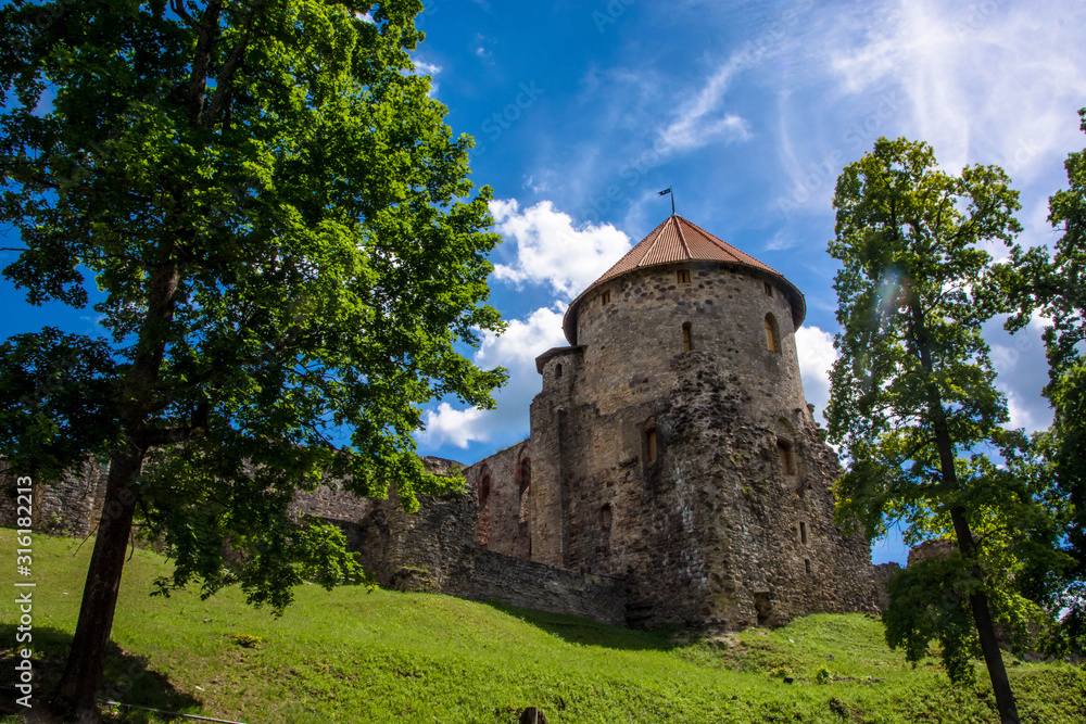 Fototapeta premium Medieval architecture. Castle in Europe. Summer Cesis, Latvia. Green trees. Sunny day. Under view.