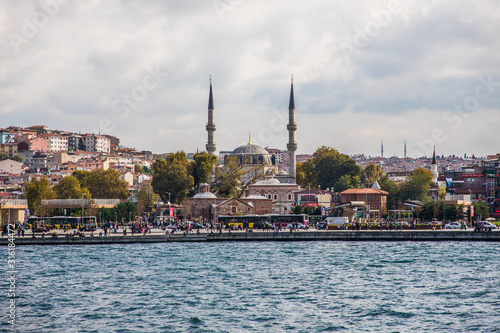 Tourist ship sails on the Golden Horn, Istanbul, Turkey. Scenic sunny panorama of Istanbul city in summer. Beautiful waterfront of Istanbul at sunset. Concept of traveling and vacation in Istanbul.