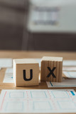 Selective focus of cubes with ux letters and layouts of user experience design on table