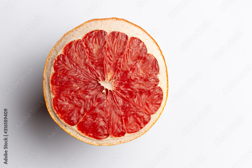 Slice of red dry grapefruit on gray background with shadow Slice of red dry grapefruit on gray background with shadow