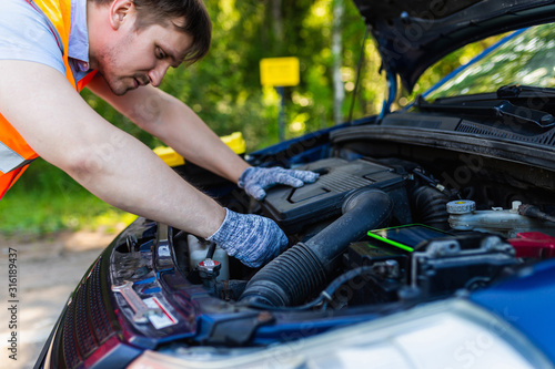 The mechanic fixes the car engine with a special key. Hands mechanic with a wrench tighten the bolts.