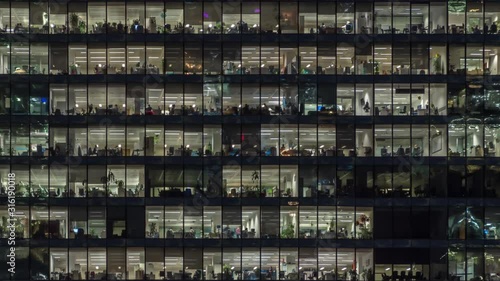 Panning to right view of office windows with working people