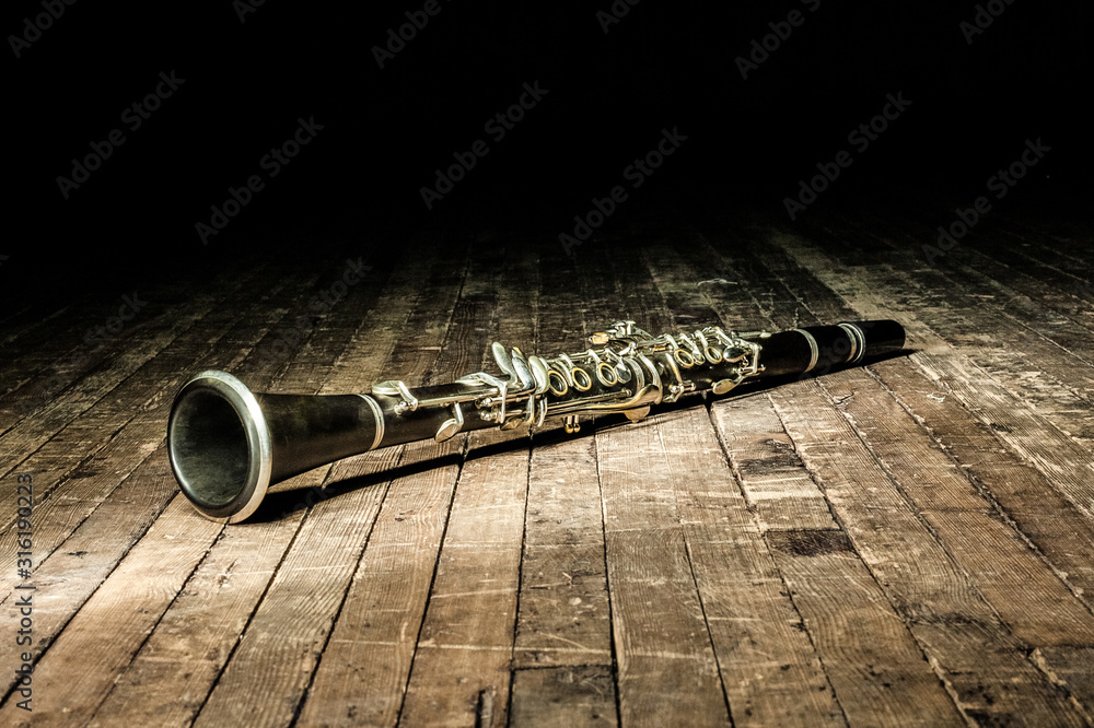 black woodwind clarinet lies on a brown wooden stage - obrazy, fototapety, plakaty 