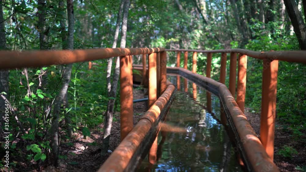 Cold water canal with railings in forest. Disease prevention healthy path