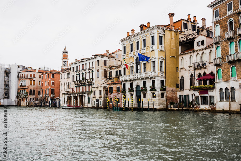 canal and ancient buildings with flags in Venice, Italy