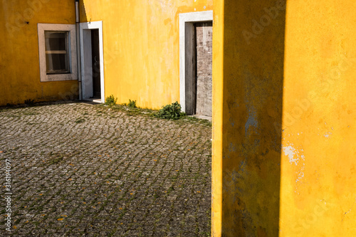Outside view of deserted house with old and grungy yellow wall, window and worn door. Abandoned place .