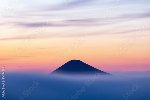 Mountain top over fog and cloud landscape after sunset. Carpathian mountains, view of Mount Hoverla, Ukraine