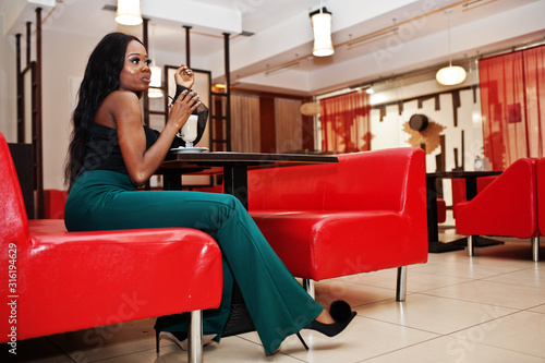 Beauty slim african american model wear on black blouse and green long legs pants drinking latte at chinese cafe.