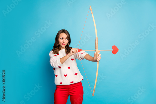 Portrait of her she nice attractive lovely charming winsome lovable cute focused cheerful cheery foxy cunning girl shooting amorous arrow isolated on bright vivid shine vibrant blue color background photo