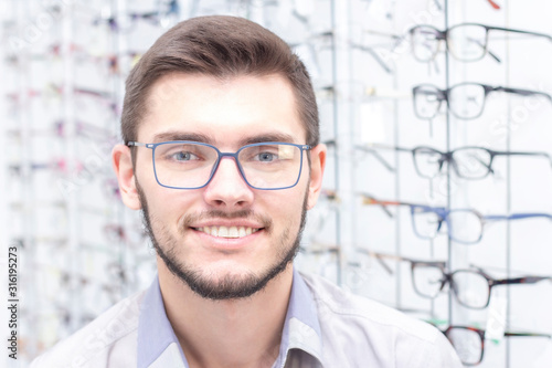 healthcare, people, vision and vision concept. men smiling trying on glasses in the store.