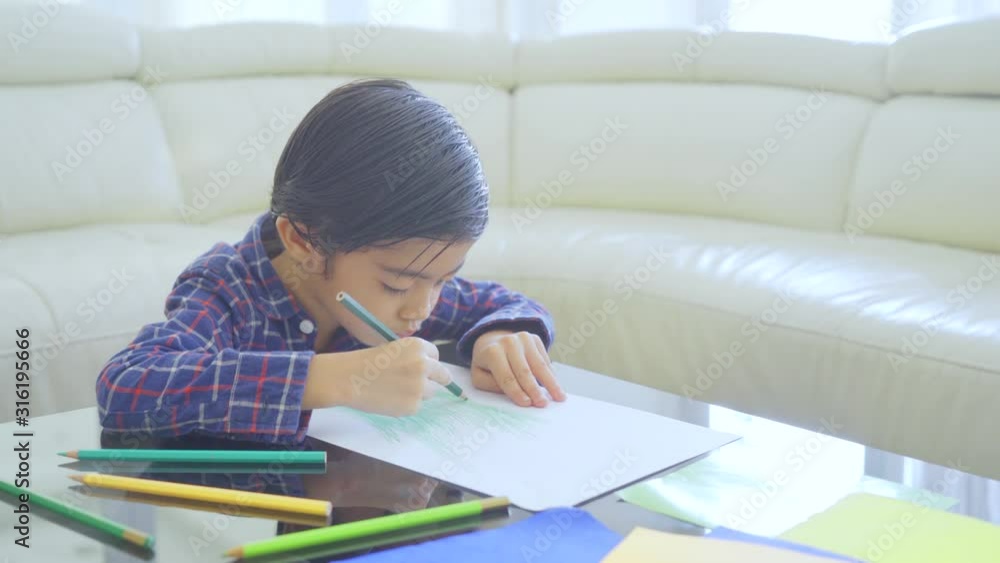 Asian little boy coloring on a paper while sitting in the living room at home. Shot in 4k resolution Asian little boy coloring on a paper while sitting in the living room at home. Shot in 4k resolution