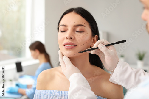 Plastic surgeon applying ma...