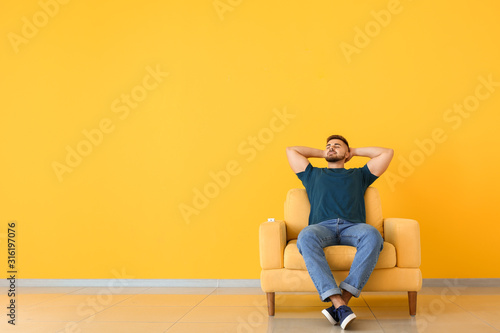 Young man relaxing in room with operating air conditioner