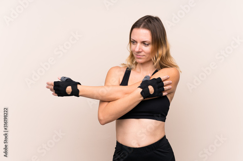 Blonde sport woman over isolated background stretching arm