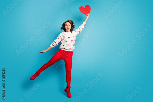 Full length body size view of nice cheerful cheery dreamy funny girlish girl jumping holding in hand heart celebratory fest having fun isolated on bright vivid shine vibrant blue color background