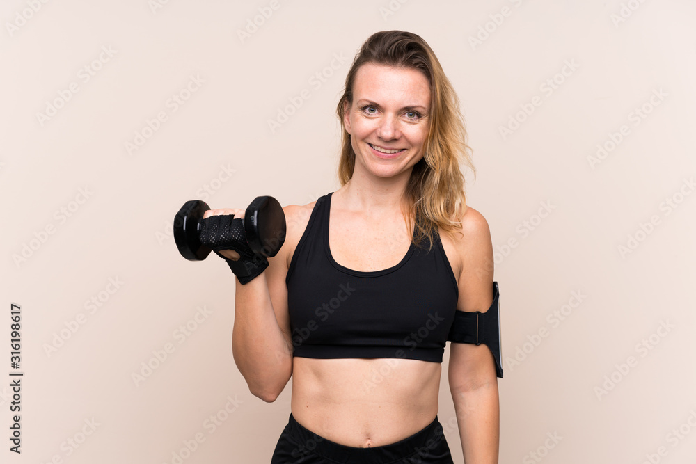 Fototapeta premium Blonde sport woman over isolated background making weightlifting