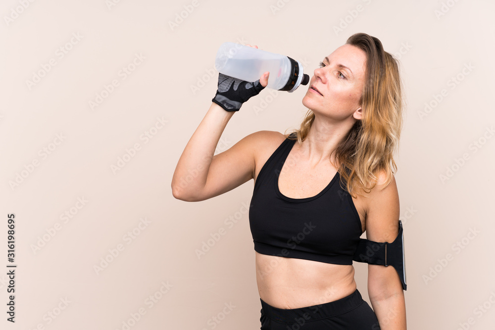 Blonde sport woman over isolated background with sports water bottle Blonde sport woman over isolated background with sports water bottle