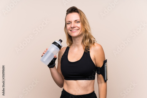 Blonde sport woman over isolated background with sports water bottle