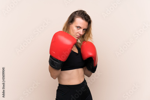Blonde sport woman over isolated background with boxing gloves © luismolinero