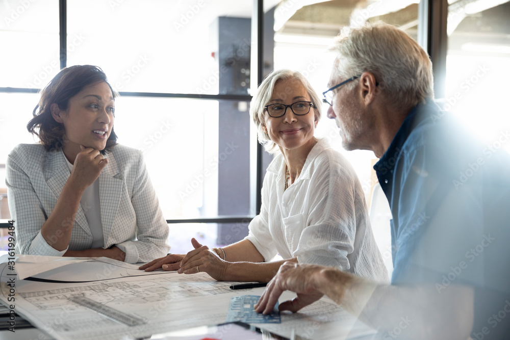 Clients discussing plans with design professional in studio Stock Photo ...