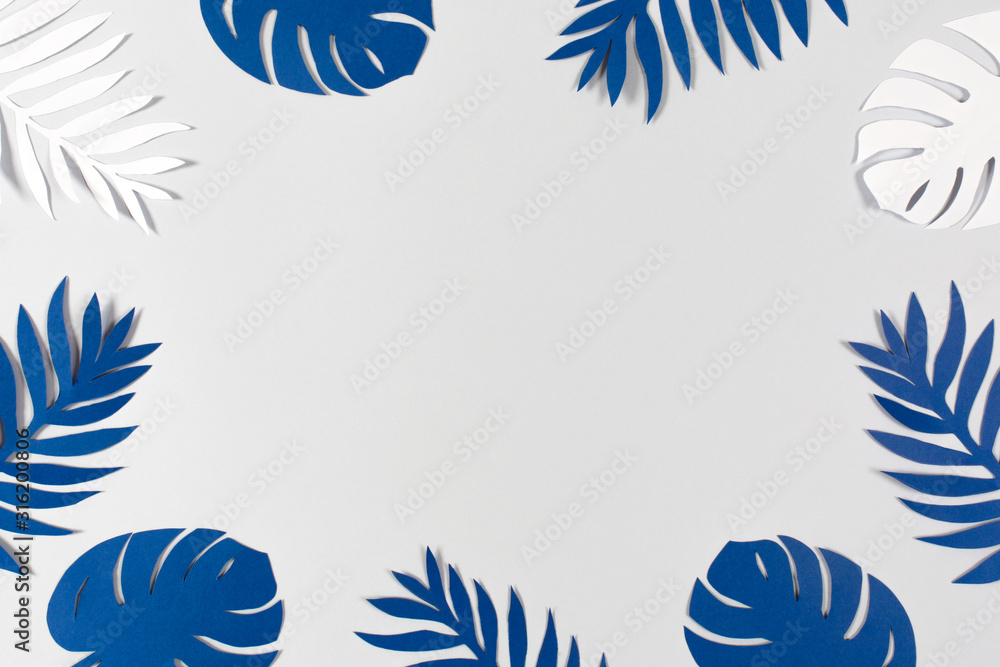 Tropical paper leaves on gray background. Color of the year 2020 - Classic Blue. Color trend palette. Top view, flat lay. 