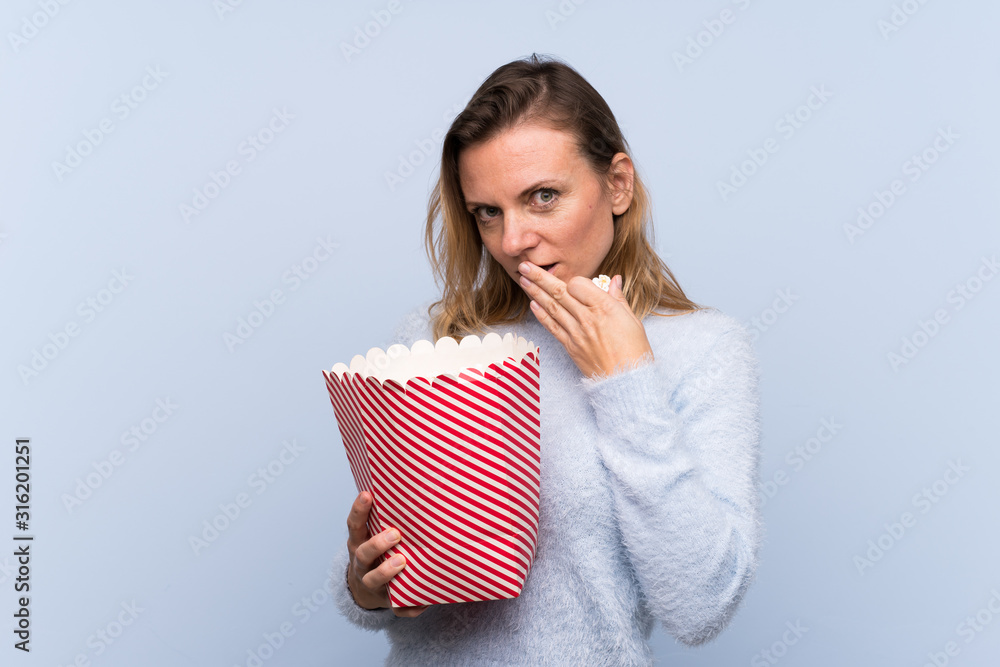 Blonde woman over isolated background holding a big bucket of popcorns Blonde woman over isolated background holding a big bucket of popcorns
