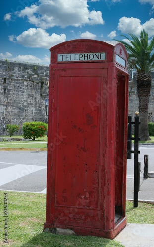 An old fashioned red telephone booth in a public park