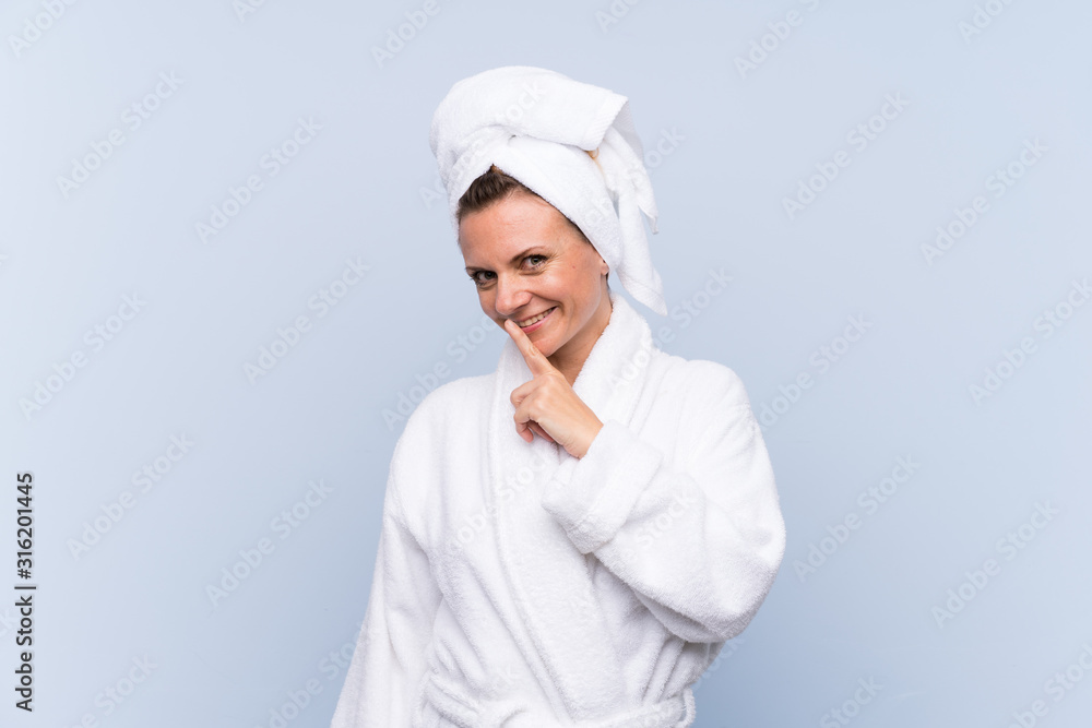 Woman in bathrobe over isolated blue background doing silence gesture Woman in bathrobe over isolated blue background doing silence gesture