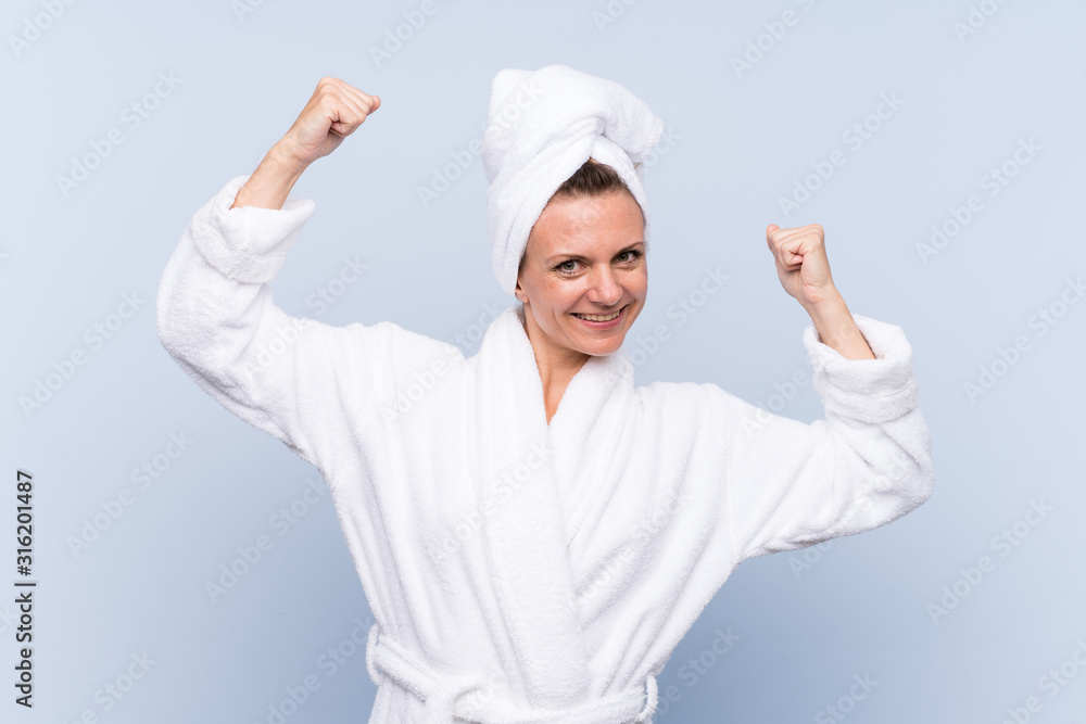 Woman in bathrobe over isolated blue background celebrating a victory Woman in bathrobe over isolated blue background celebrating a victory