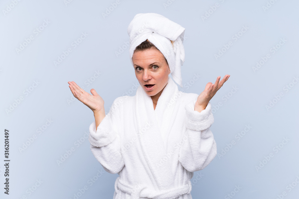 Woman in bathrobe over isolated blue background with surprise facial expression Woman in bathrobe over isolated blue background with surprise facial expression