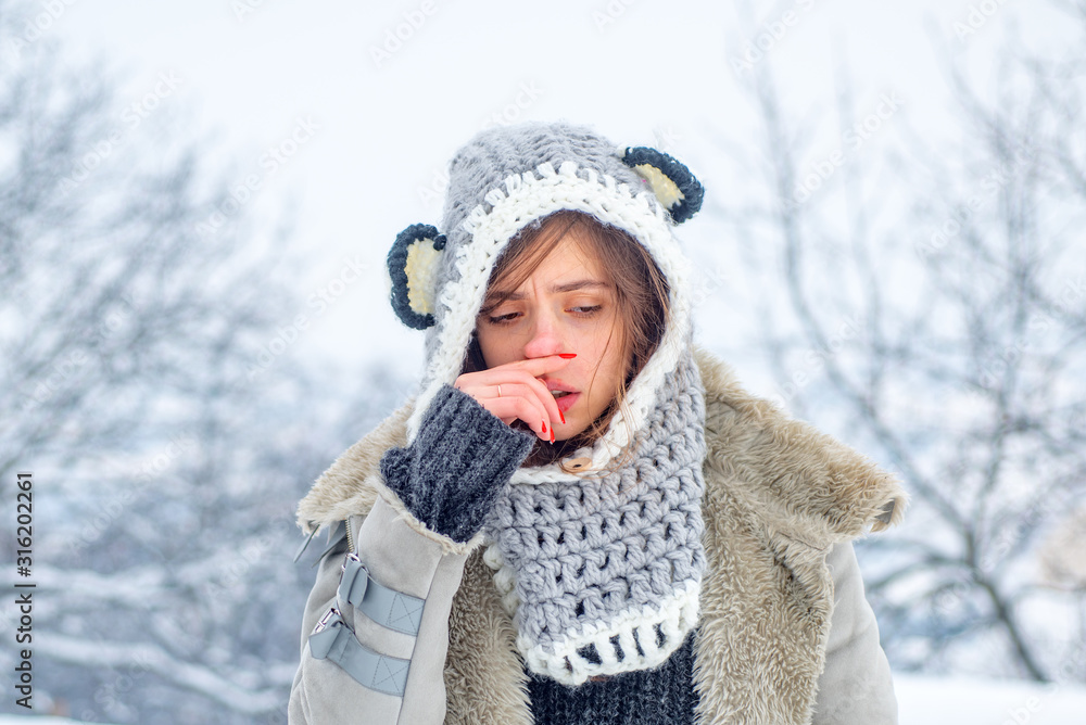 Obraz premium Cold flu winter season, runny nose. Showing sick woman sneezing at winter park.