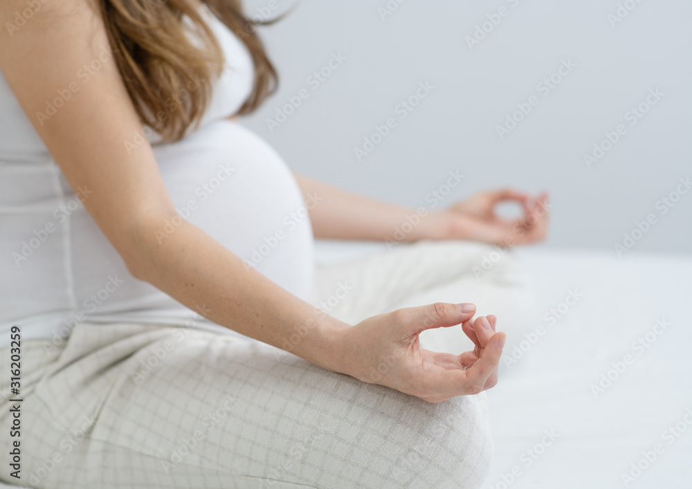 Pregnant woman practicing Yoga in the beadroom Pregnant woman practicing Yoga in the beadroom
