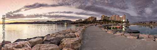 Night panoramic view from public walking pier on central beach and promenade of Eilat - famous tourist resort and recreational city in Israel