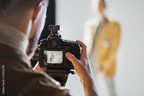 selective focus of photographer taking photo of model with digital camera on backstage photo