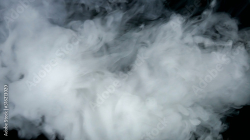 Scattering dense smoke on a black background caught in motion