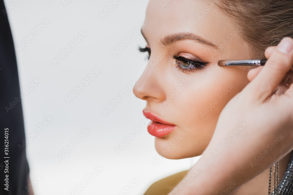 cropped view of Makeup Artist doing makeup to attractive model on backstage cropped view of Makeup Artist doing makeup to attractive model on backstage