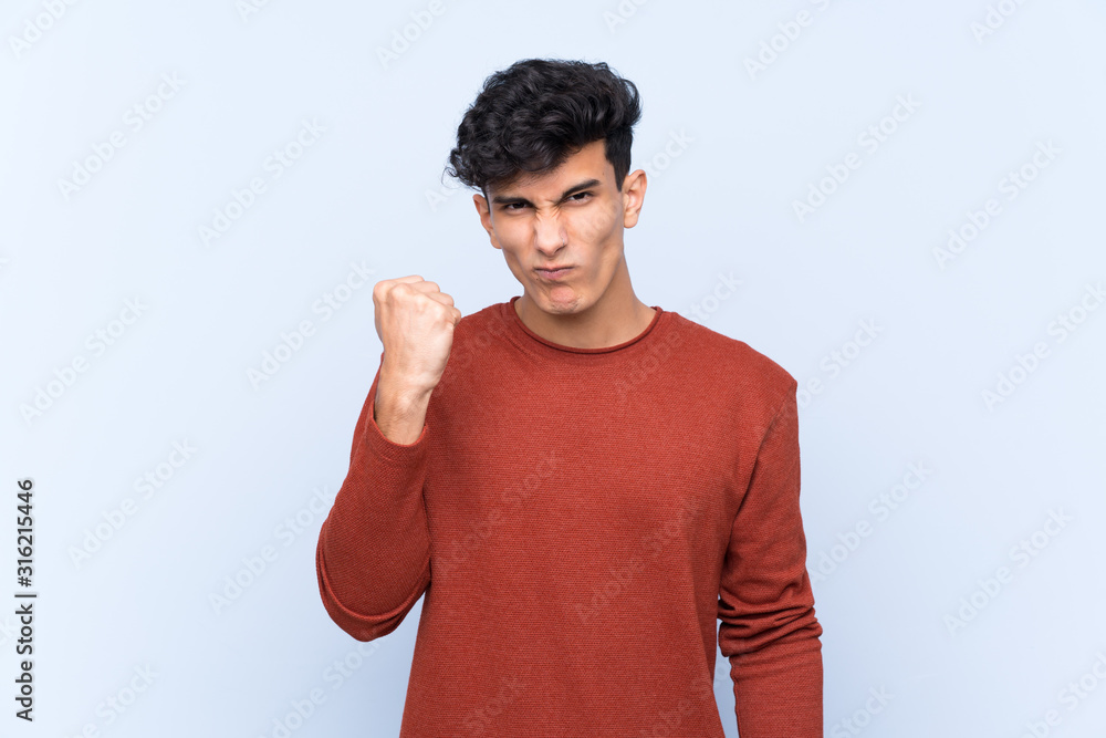 Young Argentinian man over isolated blue background with angry gesture Young Argentinian man over isolated blue background with angry gesture