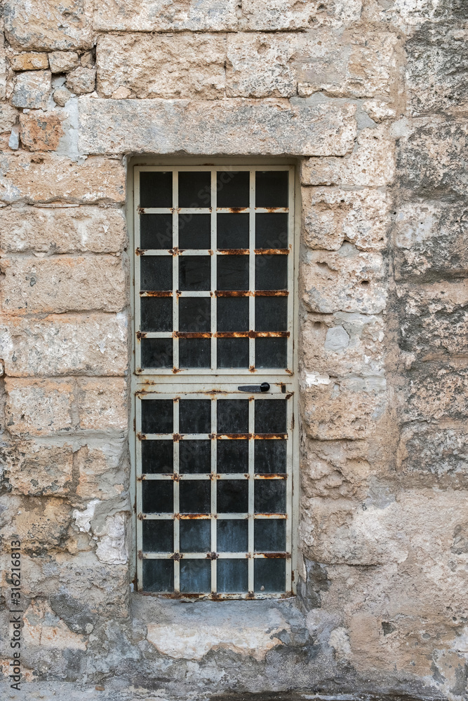 A metal door - a lattice in a stone wall of a building.