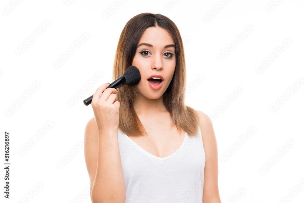 Young woman over isolated white background with makeup brush Young woman over isolated white background with makeup brush