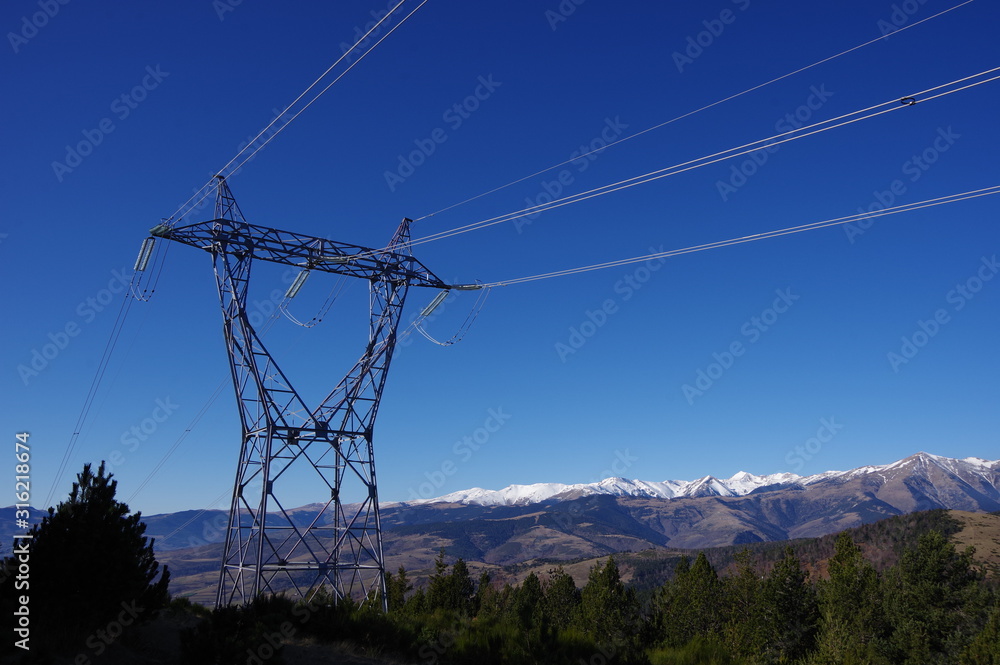 Poteau en métal de ligne électrique d'énergie de haute tension en montagne et ciel bleu