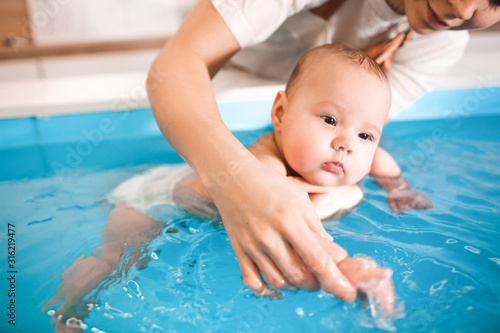 Litle baby in pool swimming bathing during health procedures.